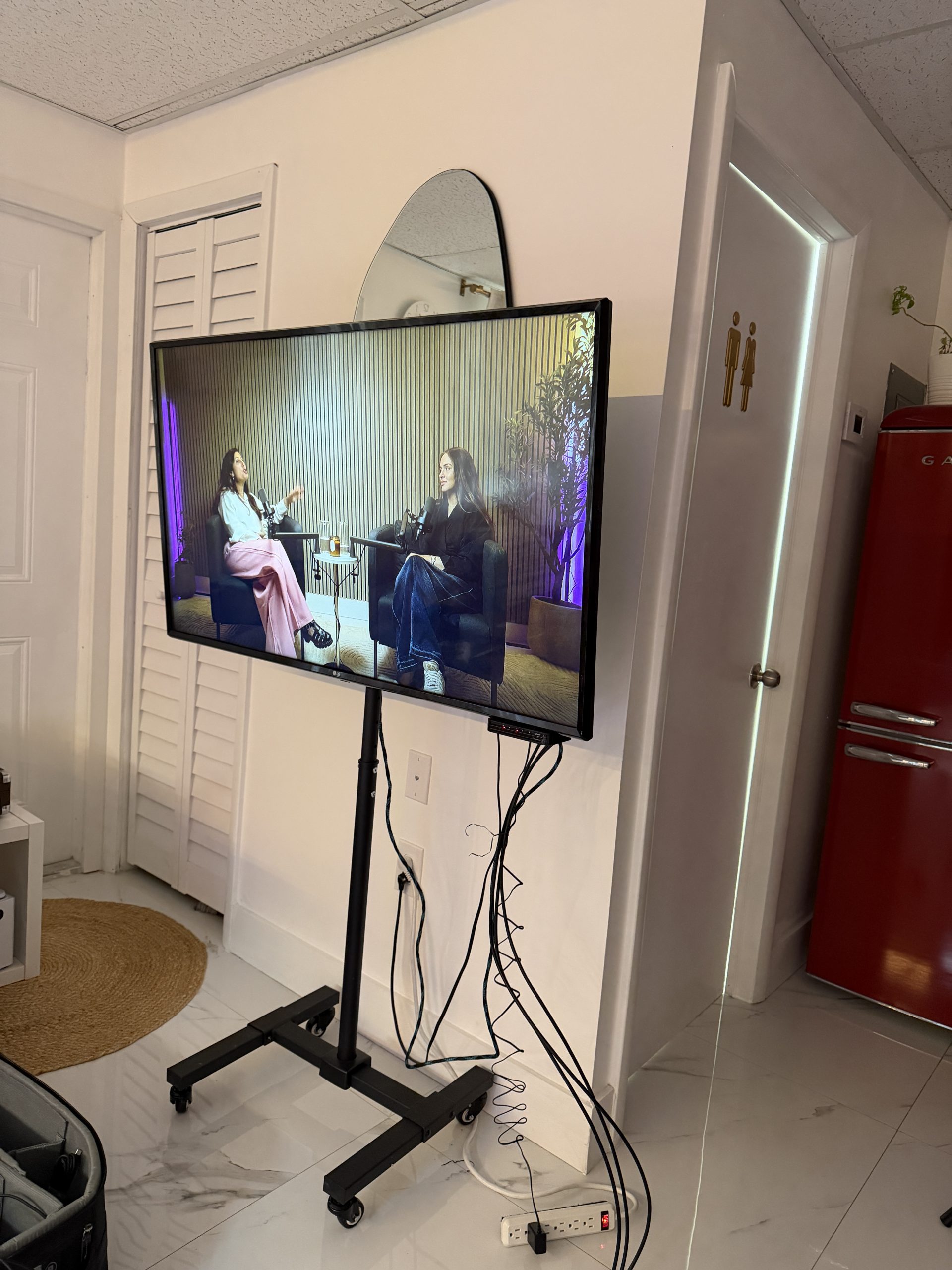 Monitor on a rolling stand displaying the live podcast recording