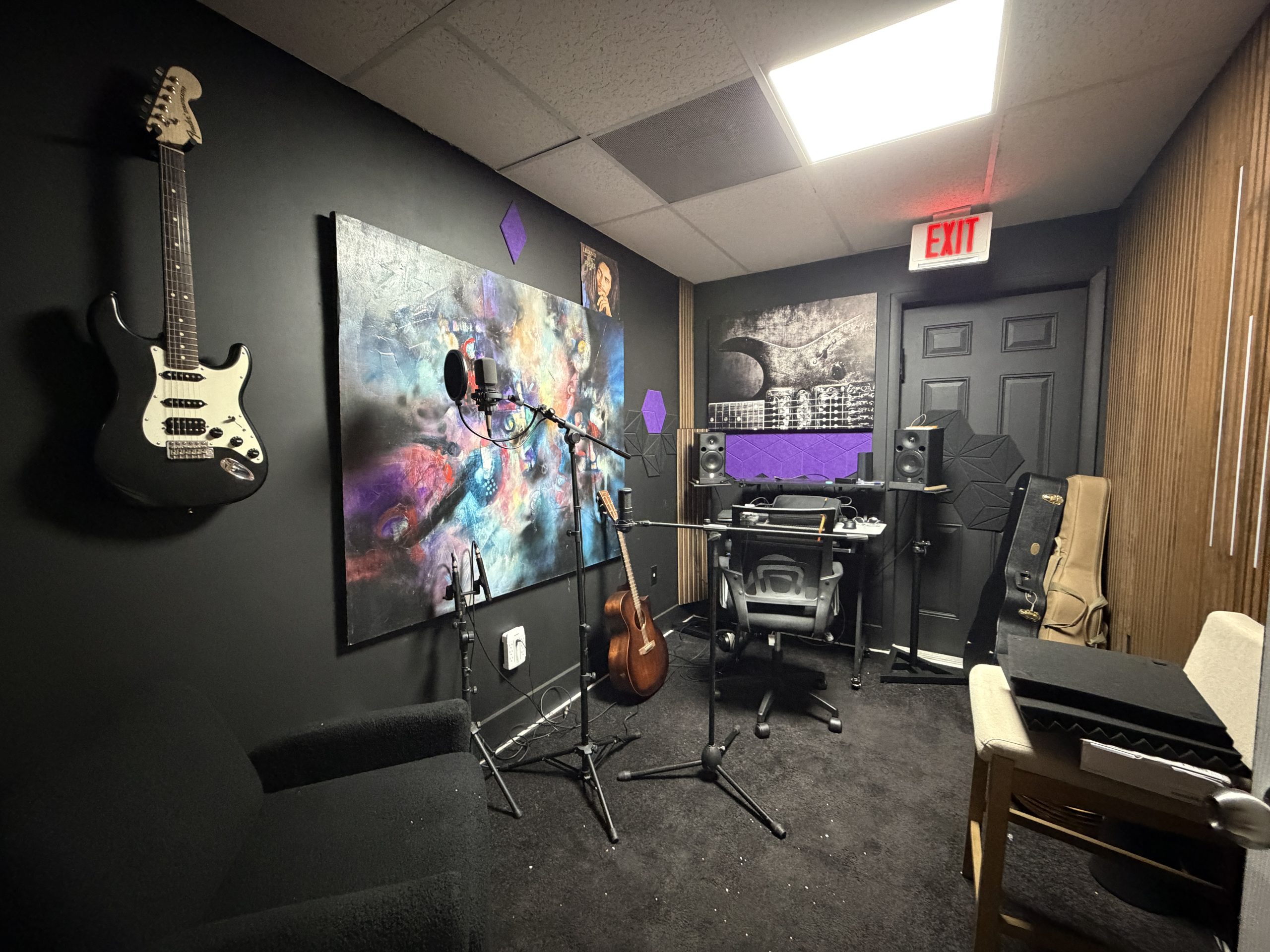 Music recording room with electric guitars mounted on the wall, a keyboard and studio desk