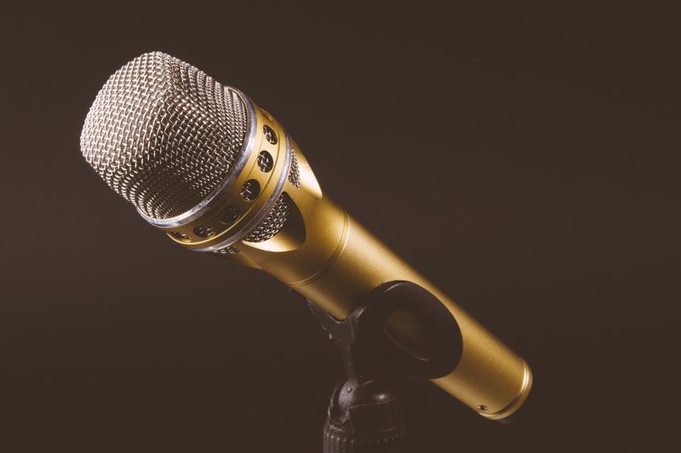 Gold coloured microphone on a stand against a dark brown background