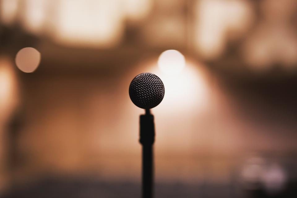 Microphone on a stand silhouetted against warm out of focus lights