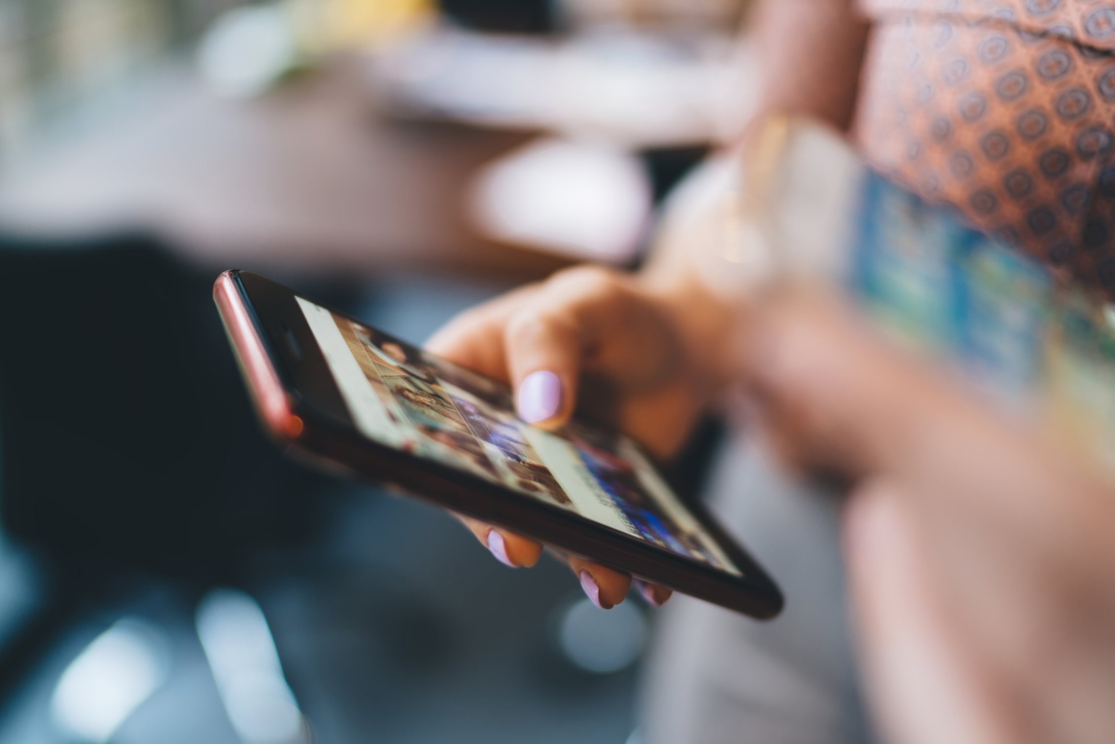 Close view of a hand holding a phone showing a grid of photos