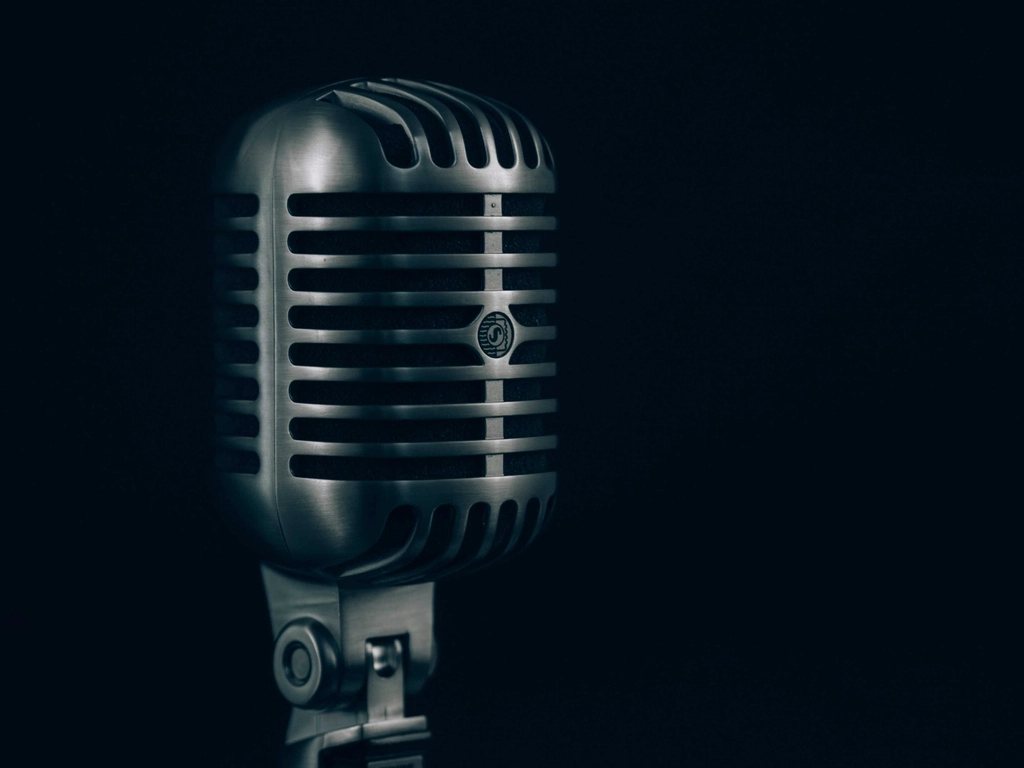Chrome retro broadcast microphone against a dark blue background
